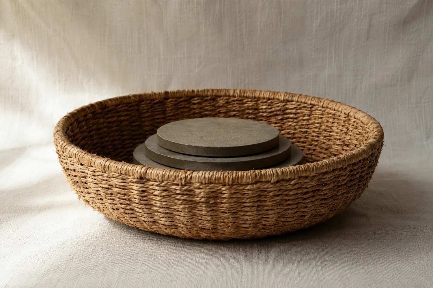 An empty round basket with flat calibration weights resting evenly across its base, photographed from the side.