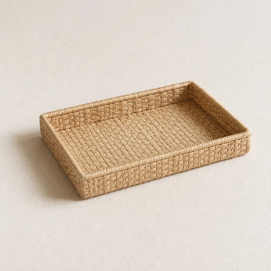 A shallow rectangular woven desk tray in pale straw fibre, shown empty from a raised angle.