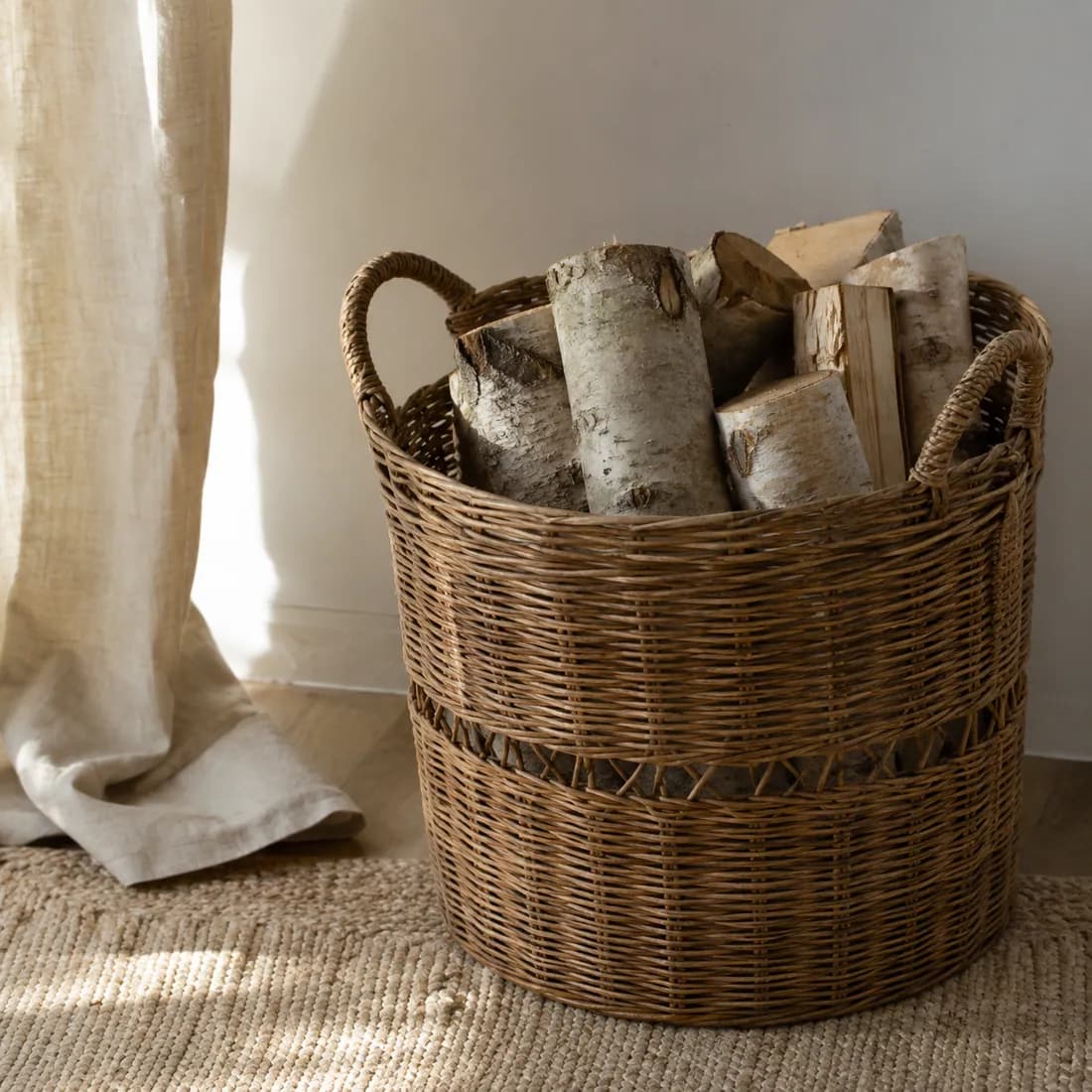Firewood Basket Ø45 — Rattan in use, loaded, photographed in a room